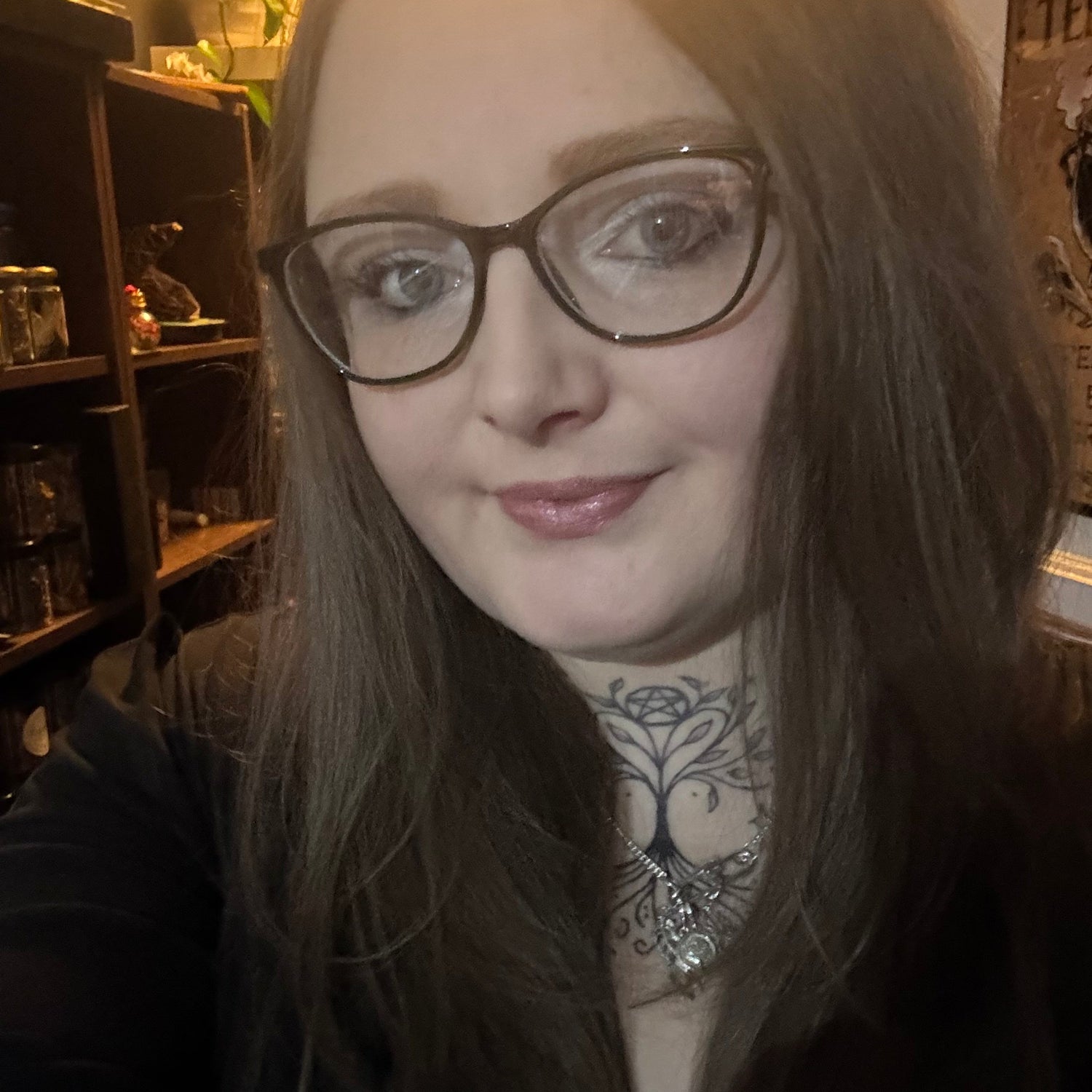 Person with glasses and tattoos in a witchy setting